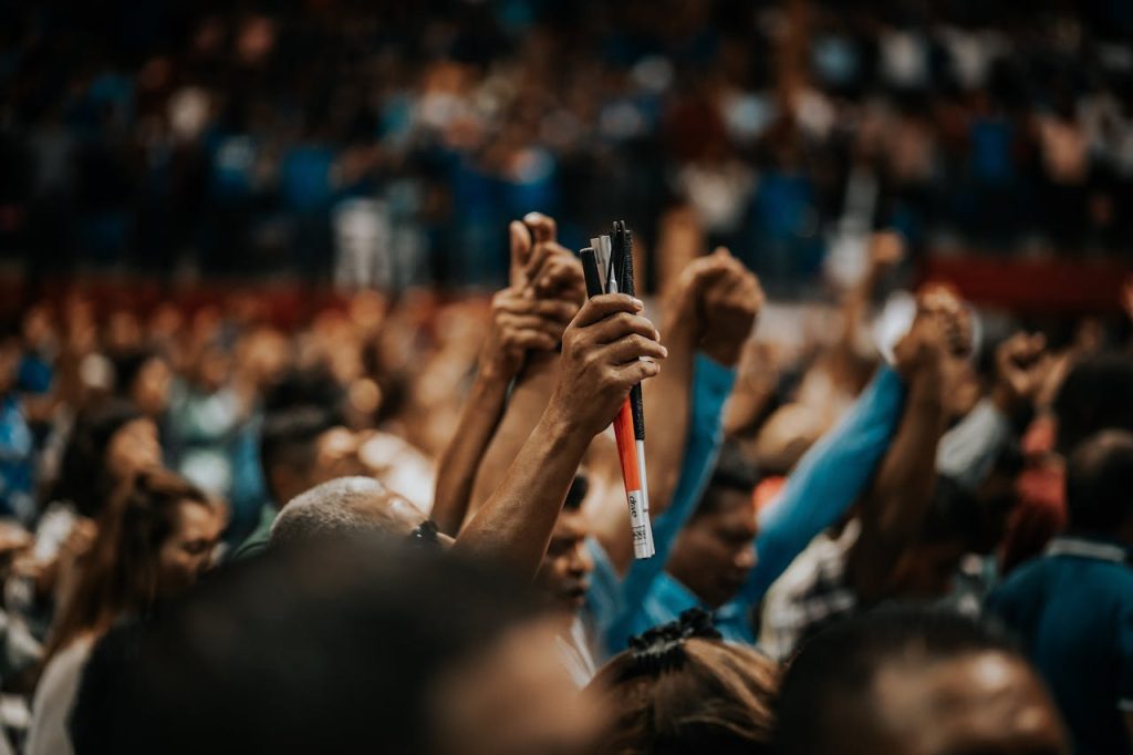 people-raising-their-hands-2330141 Energetic crowd with raised hands in a vibrant indoor gathering, symbolizing unity.