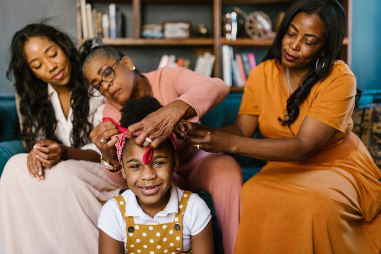 Three generations of women sharing a tender moment while fixing a young girls hair in a cozy living room.