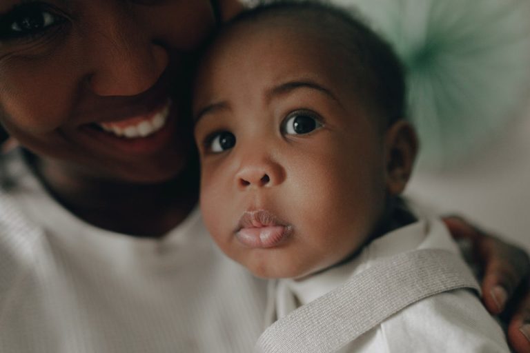 African American mother lovingly holds her baby, showcasing a close-up of faces filled with tenderness.